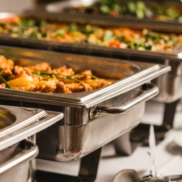 Multiple buffet chafing dishes filled with various hot dishes, including a creamy yellow curry.