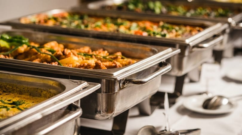 Multiple buffet chafing dishes filled with various hot dishes, including a creamy yellow curry.