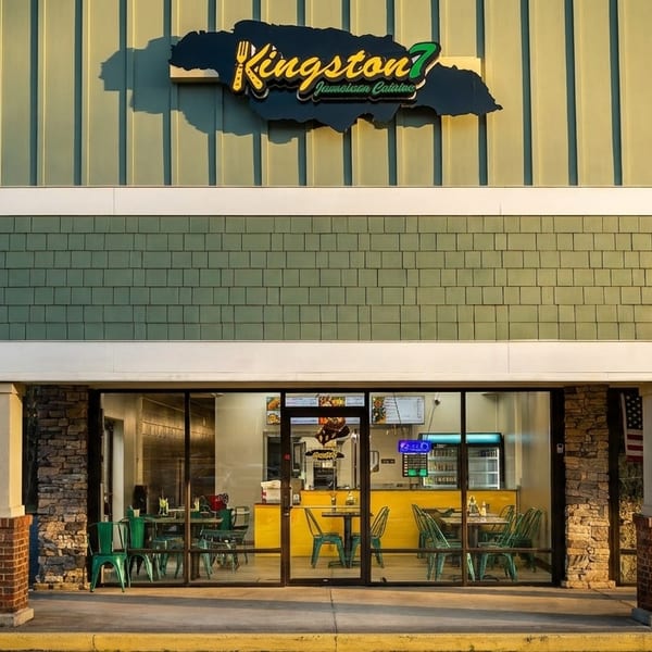 Exterior of Kingston 7 Jamaican Cuisine restaurant with green siding and a bright yellow interior.