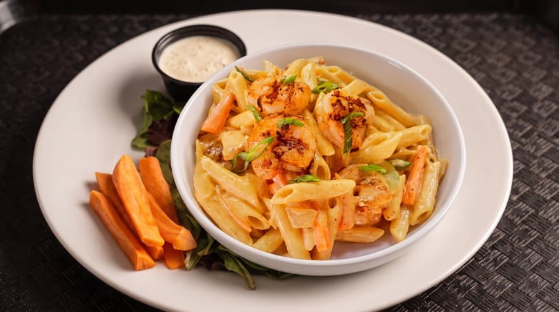 Creamy shrimp pasta with carrots and green onions, served with a side of sweet potato fries.